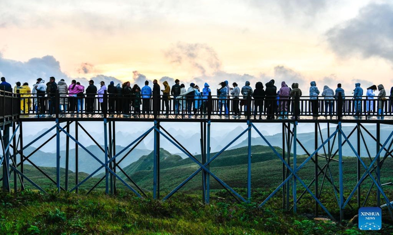 Tourists view the sunrise at a scenic spot in Hezhang County, southwest China's Guizhou Province, Sept. 4, 2021. Hezhang County, featuring beautiful natural scenery and distinctive culture, has ramped up efforts in improving tourism facilities and boosting tourism industry in recent years. Tourism development of the county has given impetus to its rural revitalization. Statistics show that the county has received 4.34 million visitor trips from January to August this year. (Xinhua/Yang Wenbin)