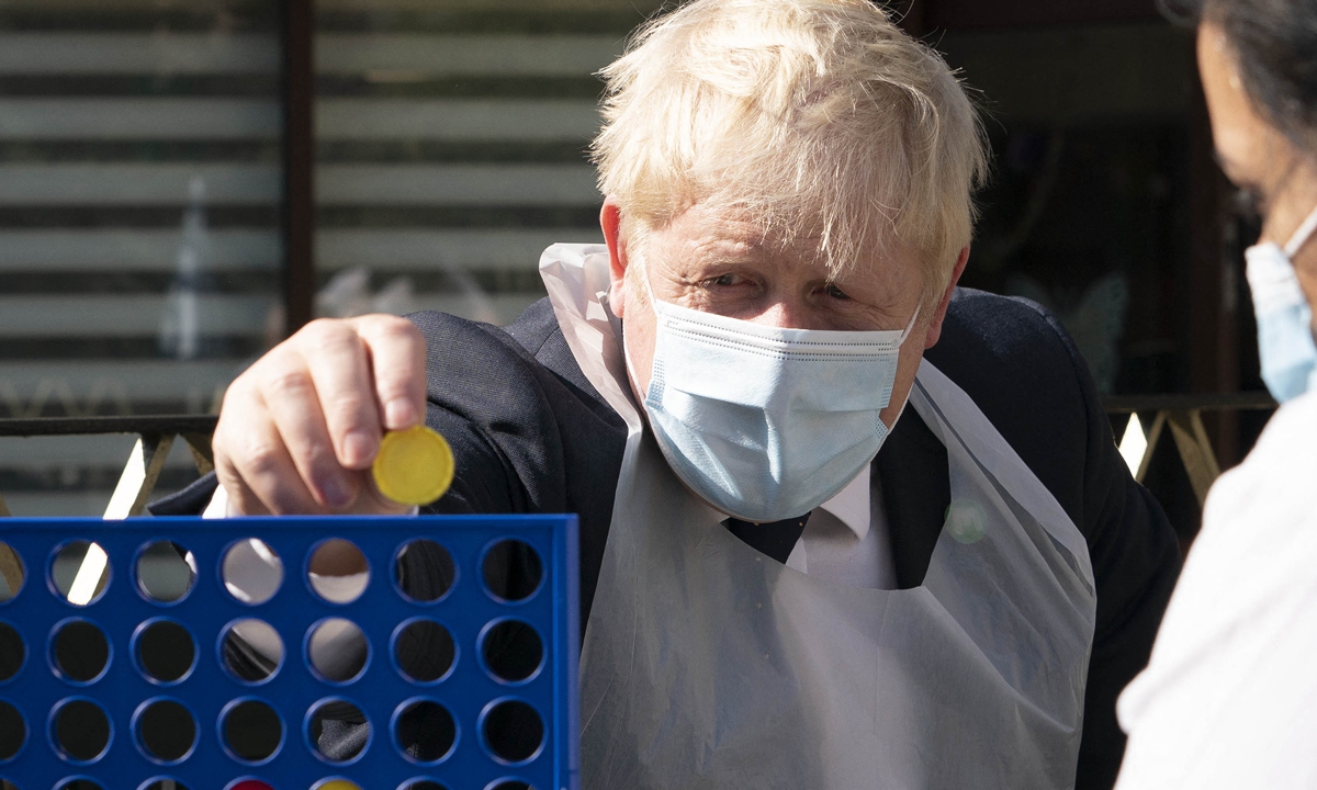 British Prime Minister Boris Johnson (left) plays a game with a resident during a visit to Westport Care Home in east London on Tuesday. Breaking an election pledge not to raise taxes, Johnson on Tuesday announced hefty new funding to fix a social care crisis and a pandemic surge in hospital waiting lists. Photo: AFP