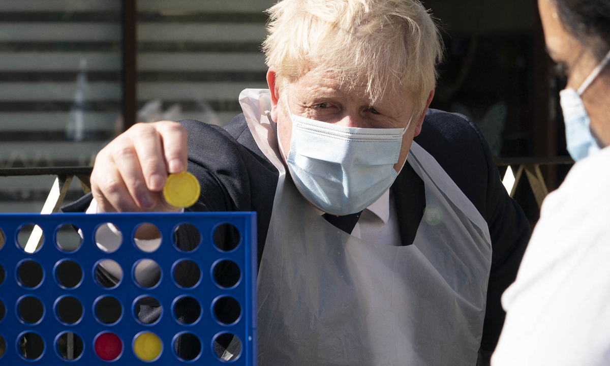British Prime Minister Boris Johnson (left) plays a game with a resident during a visit to Westport Care Home in east London on Tuesday. Breaking an election pledge not to raise taxes, Johnson today announced hefty new funding to fix a social care crisis and a pandemic surge in hospital waiting lists. Photo: AFP