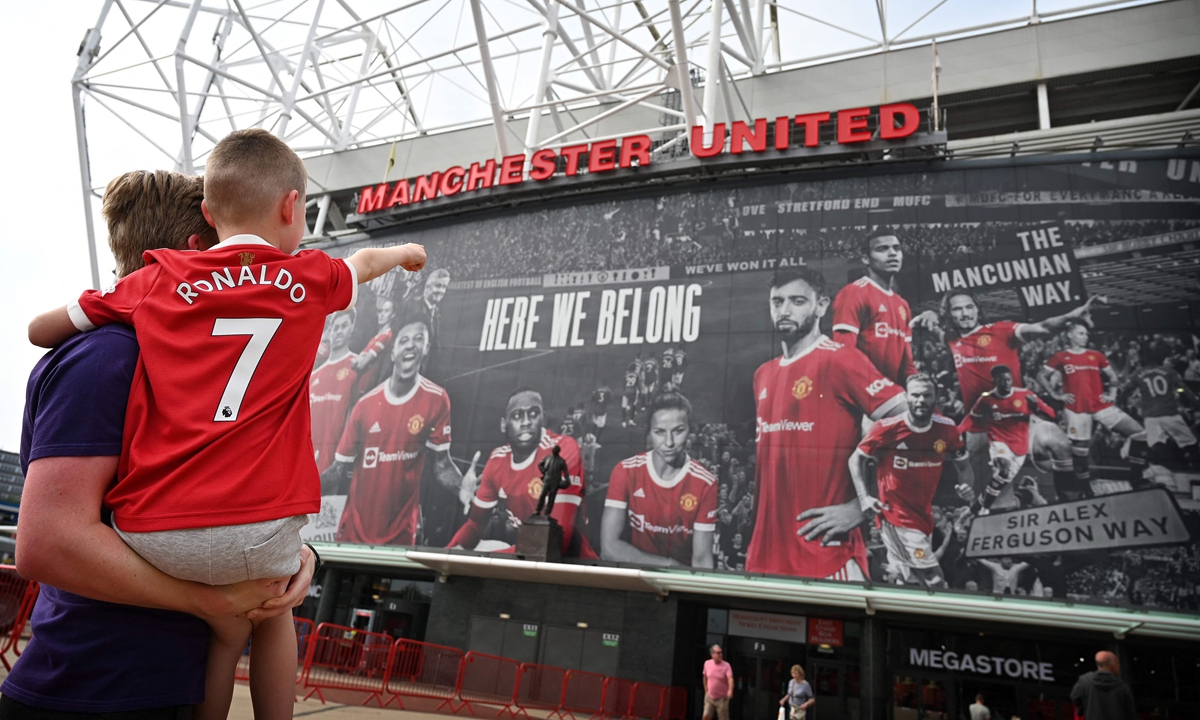 A young fan wearing the shirt of Cristiano Ronaldo points to Old Trafford stadium in Manchester, England on Monday. Photo: VCG