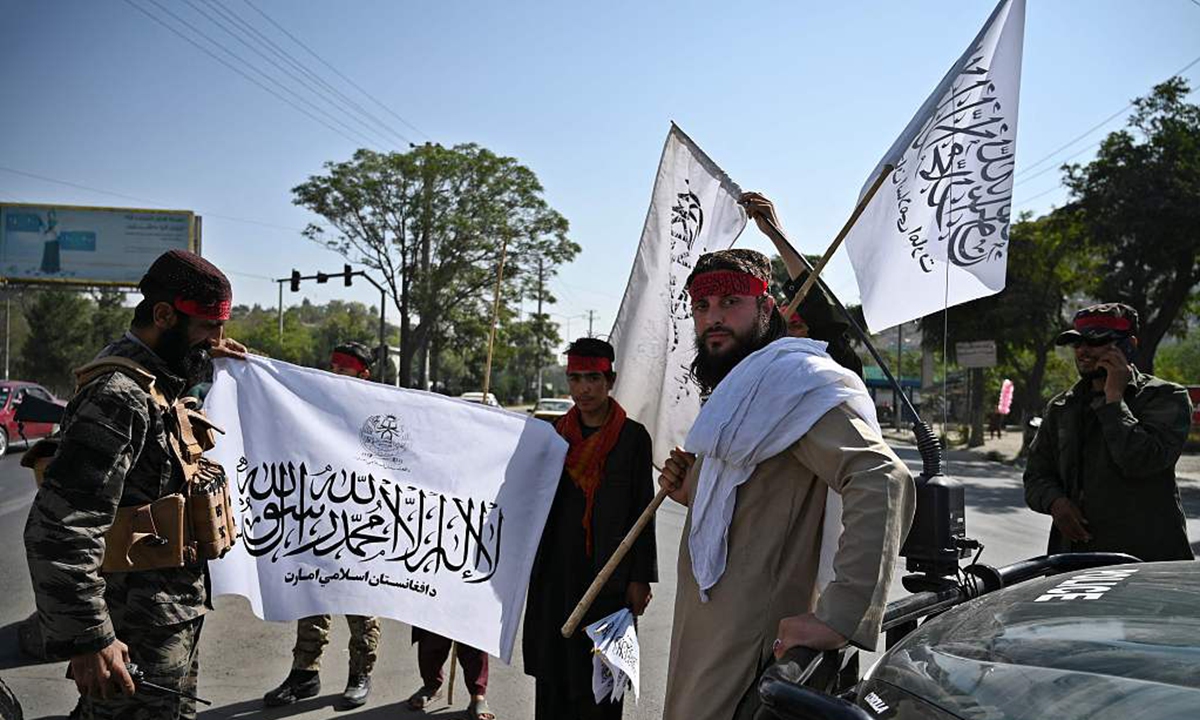 Taliban fighters hold Taliban flags while standing guard along a road in Kabul on September 9, 2021.Photo:AFP