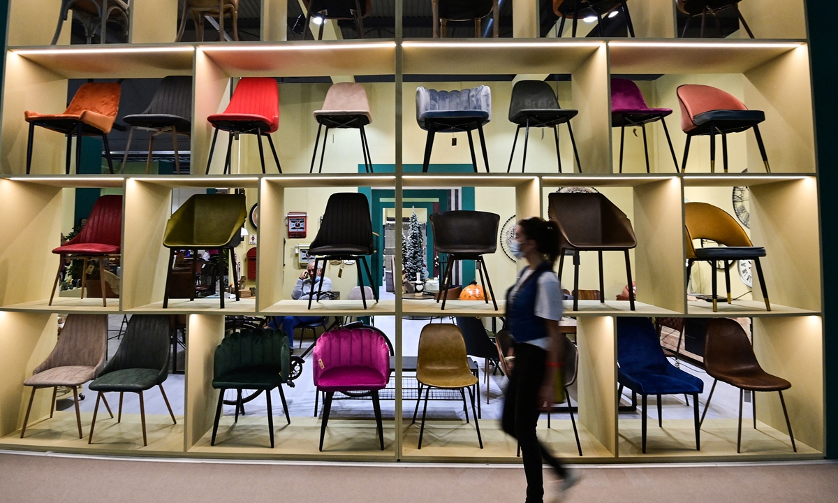 A visitor walks past chairs displayed at the stand of Novita Home at the 