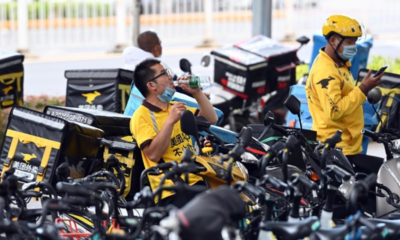 Meituan deliverymen take a break along a road in Beijing on Tuesday. Shares of the Beijing-based food delivery giant ended up 10.41 percent in the Hong Kong market on Tuesday, making it the country's third-largest internet firm by market capitalization, following Alibaba and Tencent. Photo: cnsphoto

