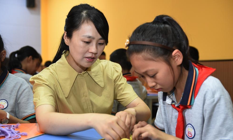 Zhao Xun (L) instructs a student in knitting techniques at the knitting club at Luogang Primary School in Hefei City, east China's Anhui Province, Sept. 8, 2021.Photo:Xinhua