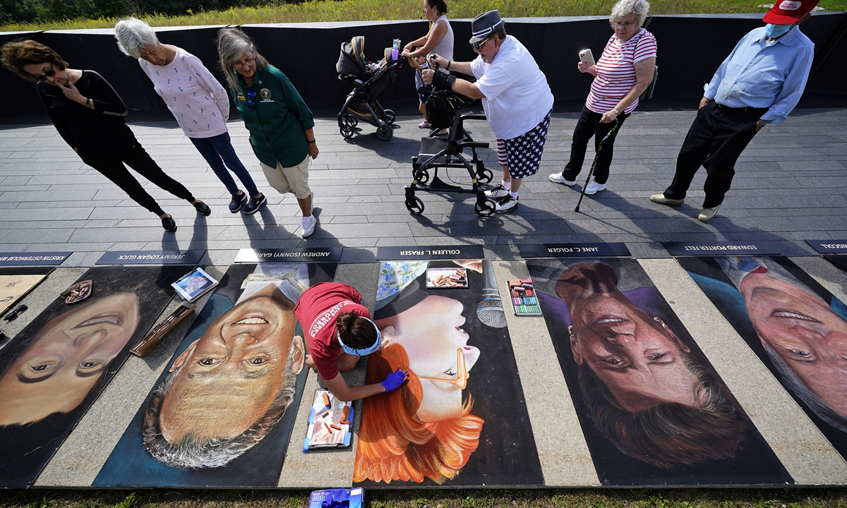 An artist (below center) works on a chalk portrait of Colleen Fraser, one of the 40 passengers and crew who perished on Flight 93, outside the Flight 93 National Memorial, in Pennsylvania, on Thursday as the US prepares to mark the 20th anniversary of the September 11 attacks. Photo: VCG