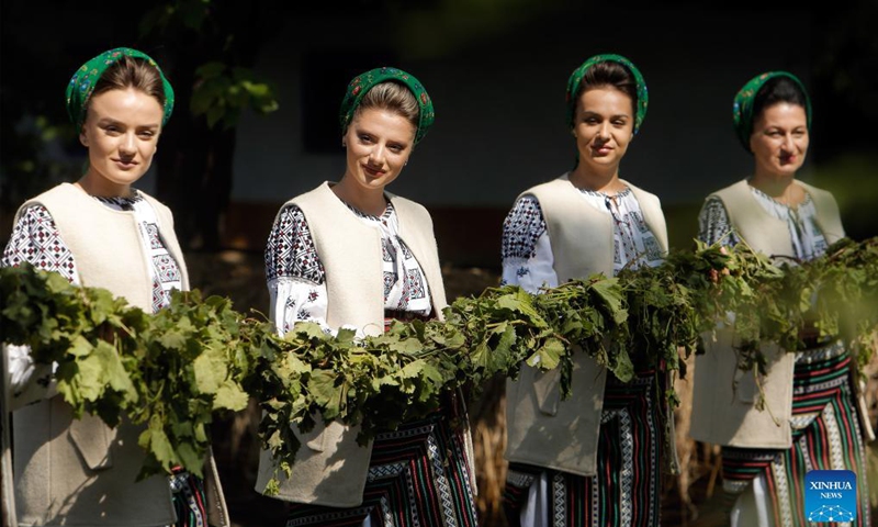 Women dressed in traditional clothes hold vine branches while performing a demonstration of ancient wine making at an autumn fair at Romanian Village Museum in Bucharest, Romania, Sept. 11, 2021.Photo: Xinhua