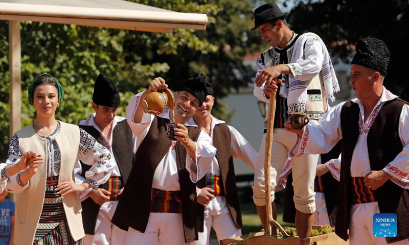 Men dressed in traditional clothes perform a demonstration of ancient wine making at an autumn fair at Romanian Village Museum in Bucharest, Romania, Sept. 11, 2021.Photo: Xinhua