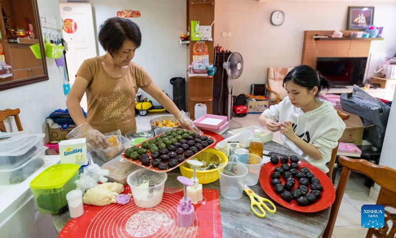 Tew Pei Yi (R) makes ice-skin mooncakes at home in Kuala Lumpur, Malaysia, Sept. 11, 2021. Tew Pei Yi was an employee of a tourism company in Malaysia until she lost her job last year as the tourism industry was badly hit by COVID-19 pandemic. With her interest in making pastries, she began to explore making mooncakes.(Photo: Xinhua)