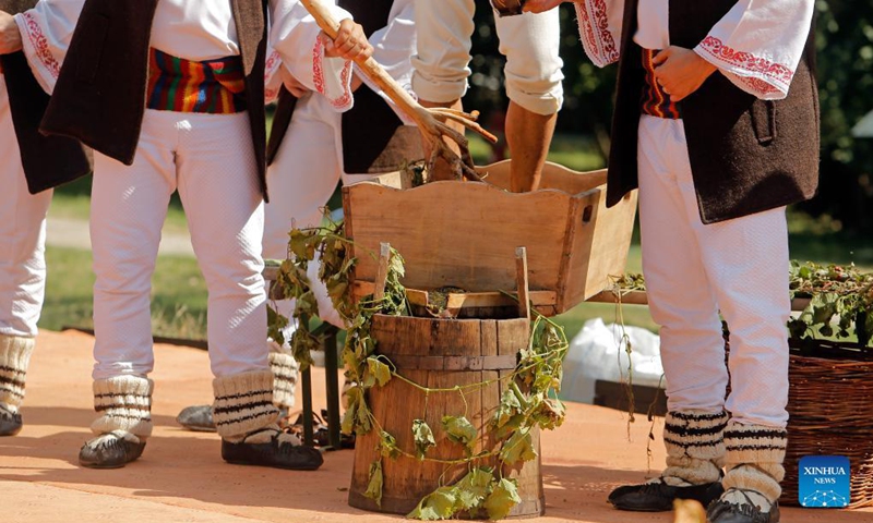 Men dressed in traditional clothes perform a demonstration of ancient wine making at an autumn fair at Romanian Village Museum in Bucharest, Romania, Sept. 11, 2021.Photo: Xinhua