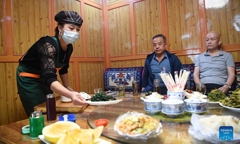 A staff member serves tea to tourists in Lisai Village of Zho'nyin County in Gannan, northwest China's Gansu Province, Sept. 11, 2021. In recent years, the local government of Lisai Village has taken advantage of the natural resources to develop rural tourism and helped increase villagers' income. Photo: Xinhua