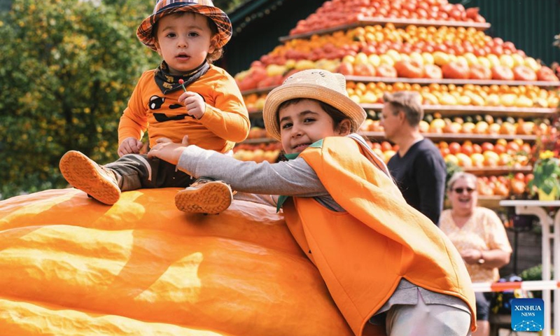 Children pose for a photo on a giant pumpkin during a traditional pumpkin festival in Lohmar, a town near Cologne, Germany, on Sept. 12, 2021.(Photo: Xinhua)