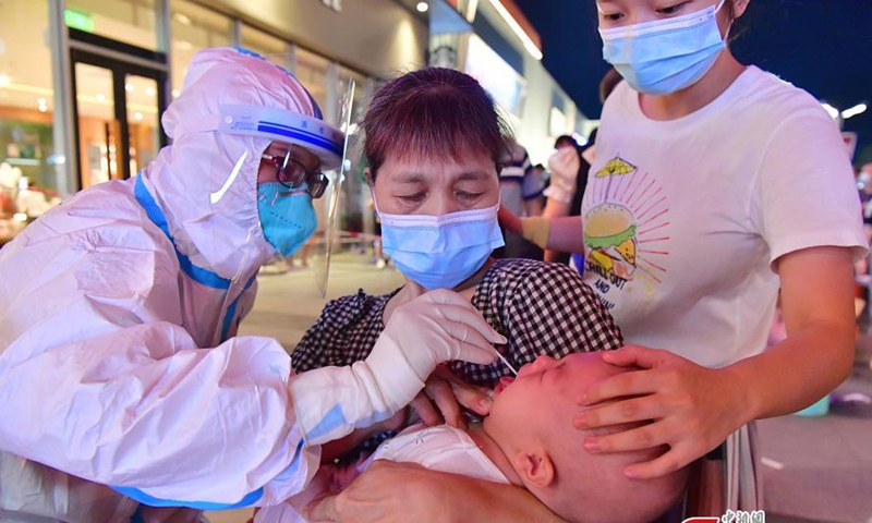 A medical worker takes a throat swab sample from a primary school studentfor nucleic acid testing in Licheng Street of Xianyou County in Putian City, East China's Fujian Province, September 12, 2021. (Photo: China News Service)