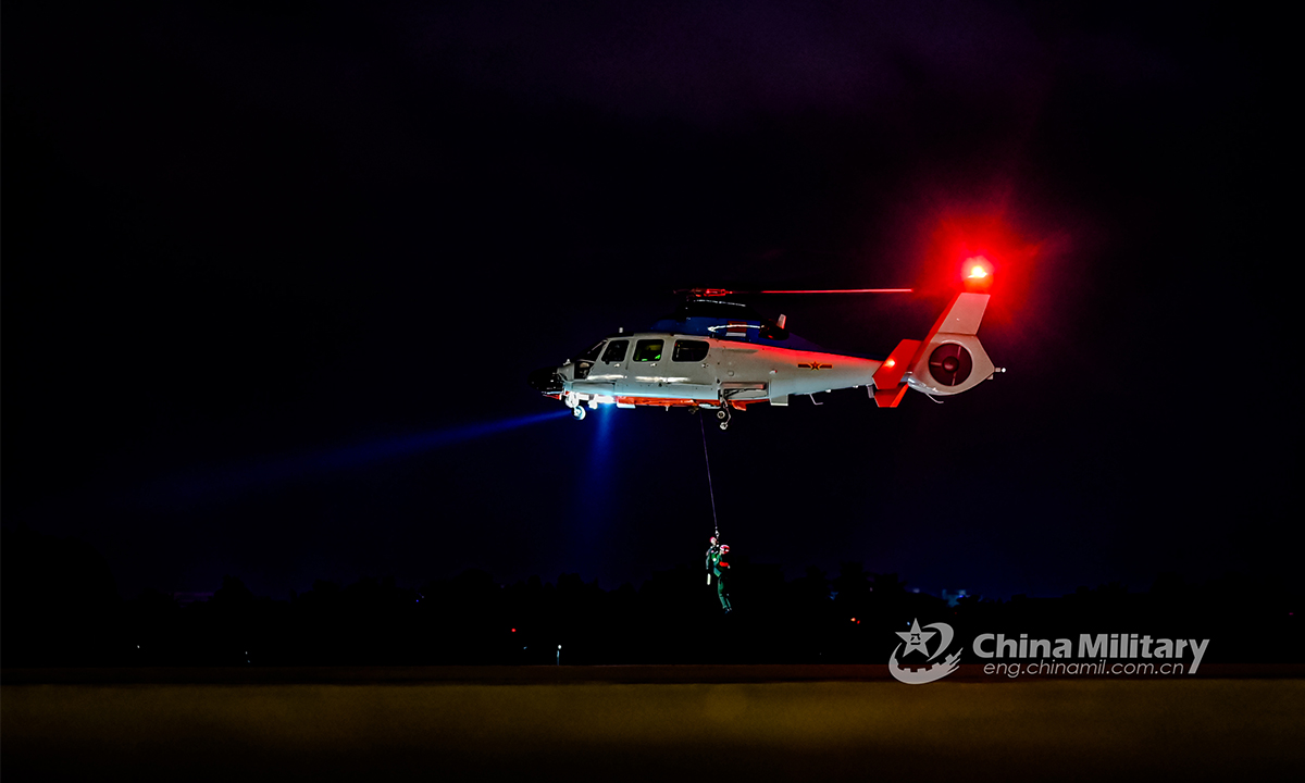 A sailor hangs from a helicopter attached to a naval aviation regiment under the PLA Northern Theater Command during a search and rescue training exercise on the night of August 24, 2021. (eng.chinamil.com.cn/Photo by Zhu Xuzhuo)