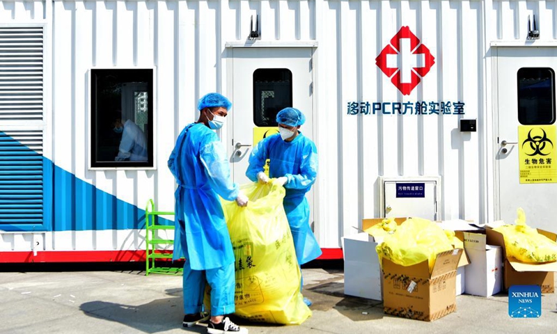 Staff members dispose medical waste outside a PCR (polymerase chain reaction) lab for nucleic acid testing in Xianyou County, southeast China's Fujian Province, Sept. 14, 2021. Three PCR labs have been built in the county to boost nucleic acid detection capacity.Photo:Xinhua