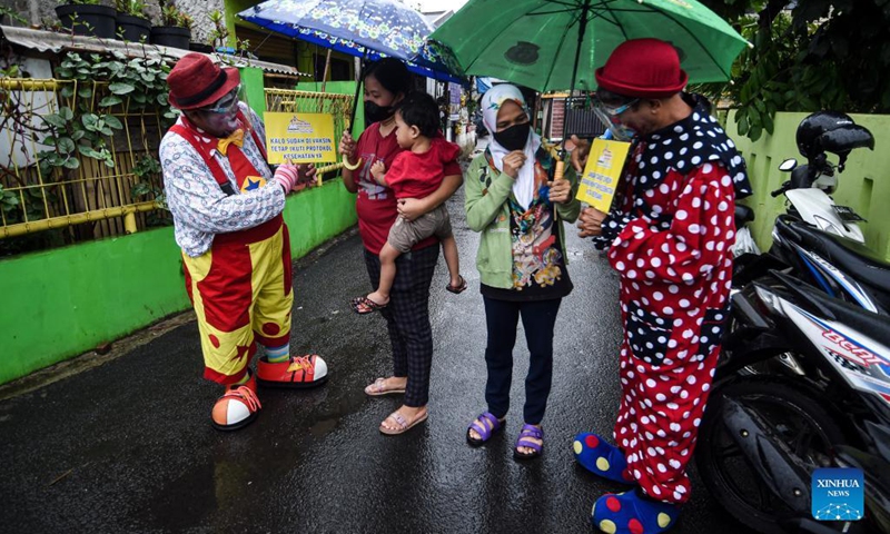 Members of a clown community holding placards with epidemic prevention and control slogans talk with residents amid a COVID-19 vaccination campaign in Tangerang, Indonesia, Sept. 14, 2021.(Photo: Xinhua)