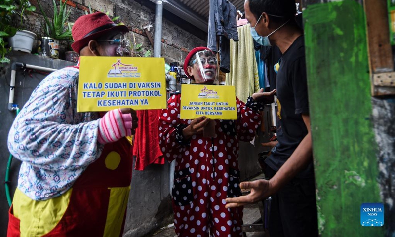 Members of a clown community holding placards with epidemic prevention and control slogans talk with a resident amid a COVID-19 vaccination campaign in Tangerang, Indonesia, Sept. 14, 2021.(Photo: Xinhua)