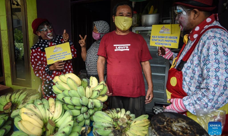 Members of a clown community holding placards with epidemic prevention and control slogans talk with residents amid a COVID-19 vaccination campaign in Tangerang, Indonesia, Sept. 14, 2021.(Photo: Xinhua)