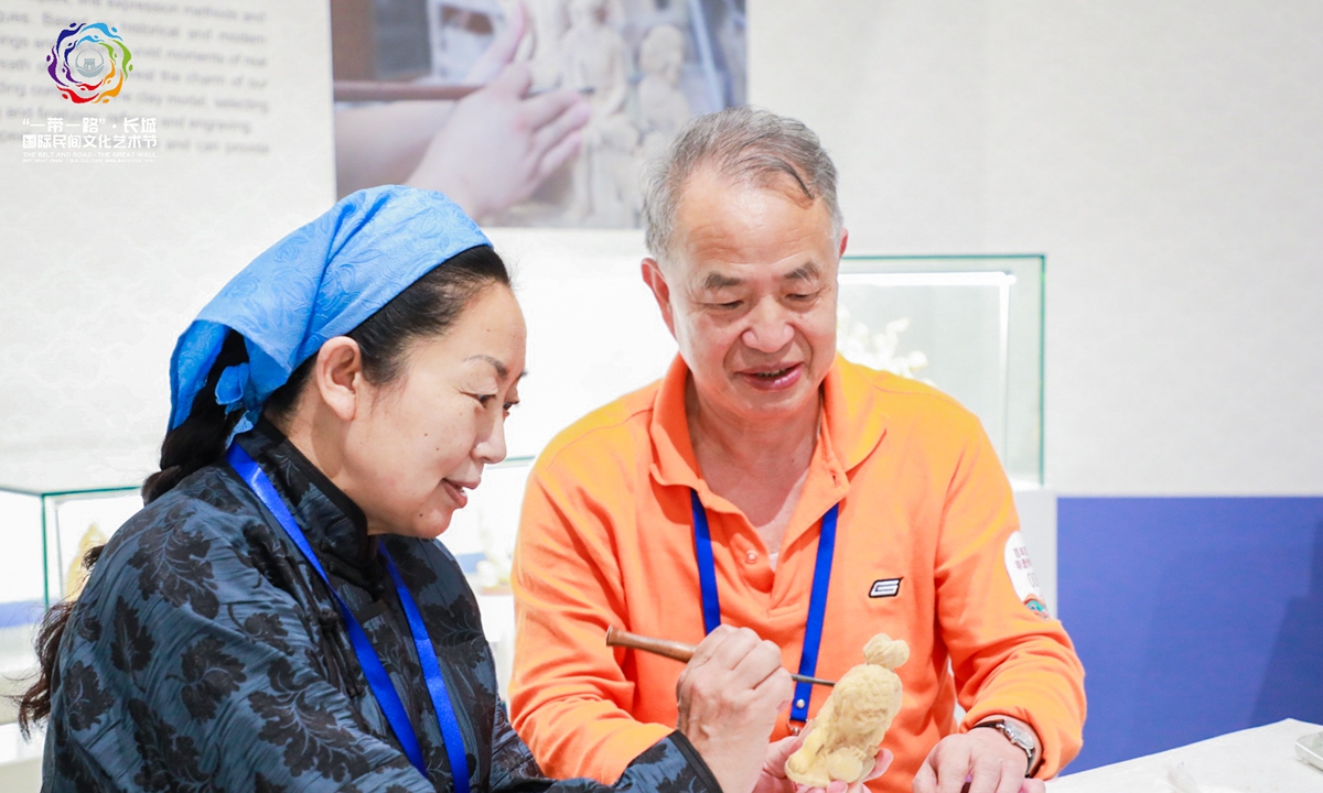 A silk market at the Belt and Road and the Great Wall International Folk Culture and Arts Festival 2021 Photos: Courtesy of Jiao Guoyuan ?A Chinese fan
?A handicraftsman shows her woodcarving skills to a visitor at the Great Wall International Folk Culture and Arts Festival 2021 in Langfang, North China's Hebei Province, on Thursday. 