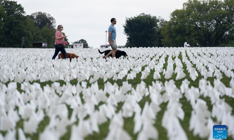 People walk past white flags on the National Mall in Washington, D.C., the United States, on Sept. 16, 2021. More than 660,000 white flags were installed here to honor the lives lost to COVID-19 in the United States. Photo:Xinhua