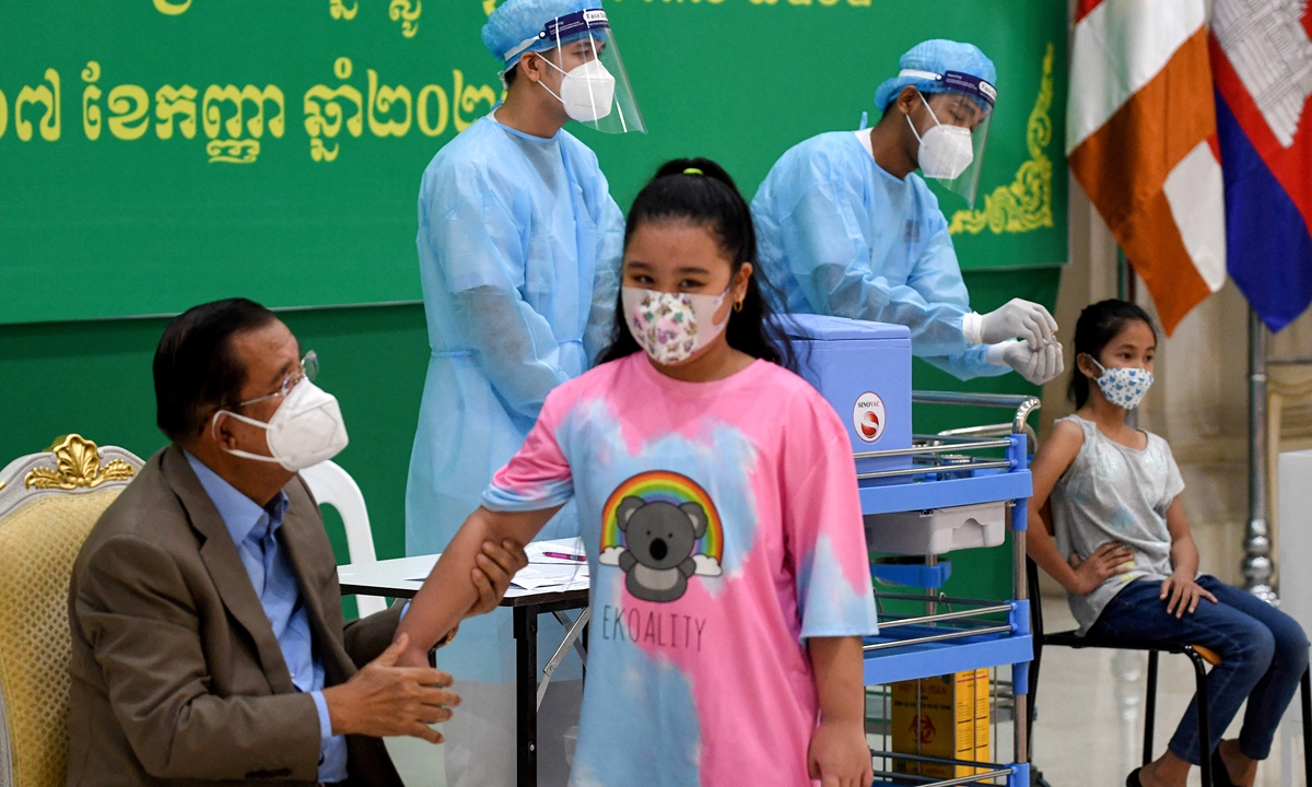 Cambodian Prime Minister Hun Sen talks to his granddaughter after she received a dose of the Sinovac Covid-19 coronavirus vaccine at the Peace Palace in Phnom Penh on Friday, as the country begins vaccinating children aged between six and 12. China donated additional 600,000 doses of COVID-19 vaccine to Cambodia on August 23. Photo: AFP