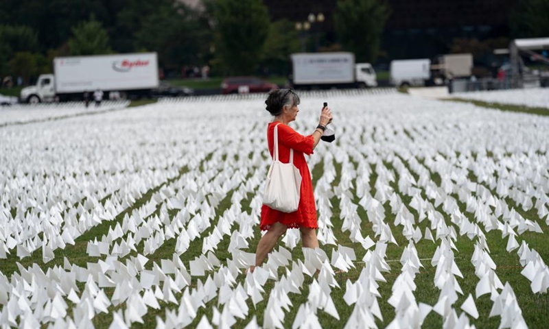A woman walks past white flags on the National Mall in Washington, D.C., the United States, on Sept. 16, 2021. More than 660,000 white flags were installed here to honor the lives lost to COVID-19 in the United States.Photo:Xinhua