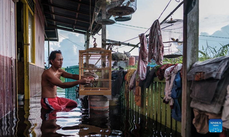 A man holds a bird cage in front of his house submerged by flood water as a result of heavy rainfall at Mendawai village in Palangkaraya, Central Kalimantan, Indonesia, Sept. 20, 2021.(Photo: Xinhua)