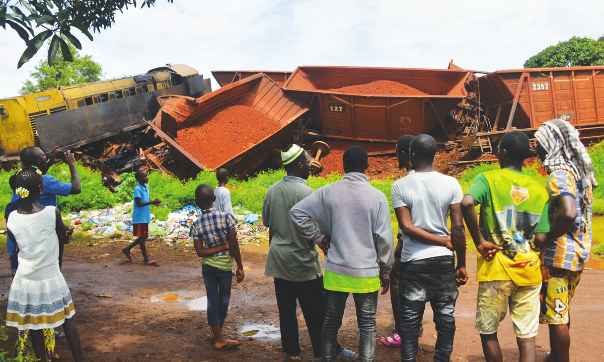 People look on at the site where a train carrying bauxite collided into a stationary train in Conakry, Guinea, on Monday. One person was killed and six were injured. Photo: VCG