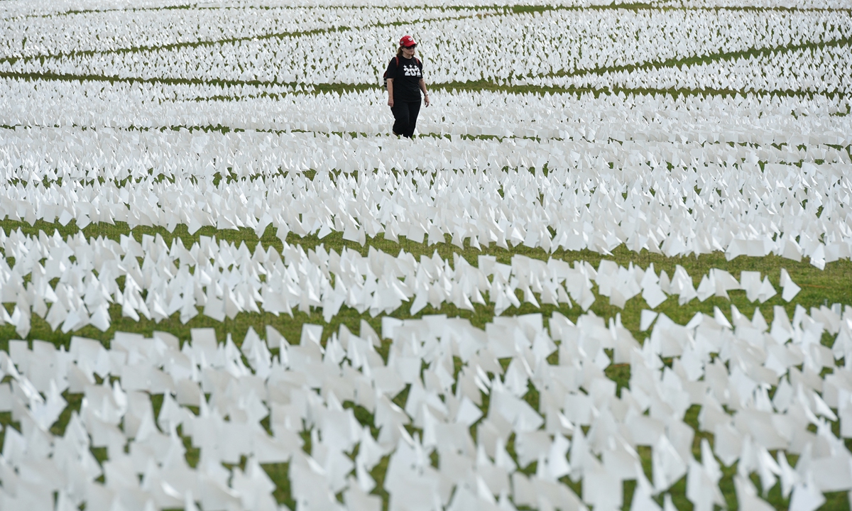 A woman walks through a field of white flags on the Mall near the Washington Monument in Washington, DC on September 16, 2021. The project, by artist Suzanne Brennan Firstenberg, uses over 600,000 miniature white flags to symbolize the lives lost to Covid-19 in the US.
MANDEL NGAN / AFP