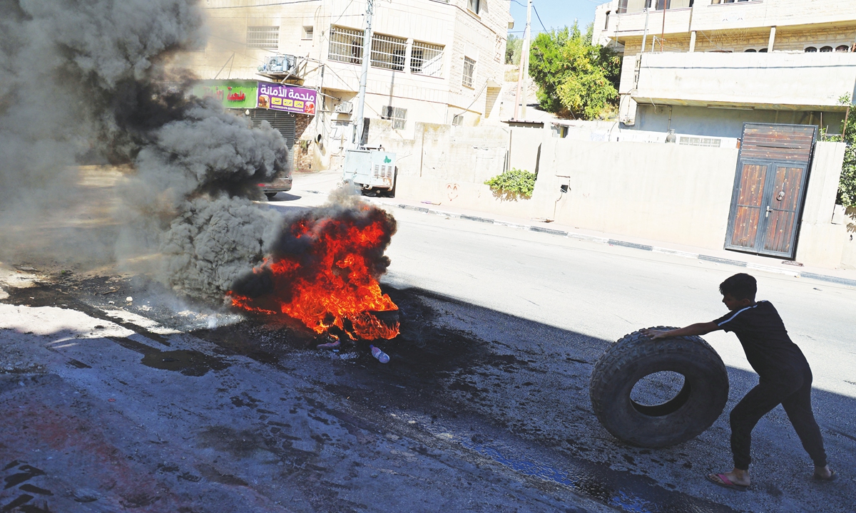 A Palestinian demonstrator burns tires at the entrance of the village of Burqin, west of Jenin, in the Israeli occupied West Bank on Sunday. The Palestinian health ministry said a Palestinian man from the village of Burqin, west of Jenin, who had been shot with a live bullet, died from his wounds after reaching hospital. Photo: AFP