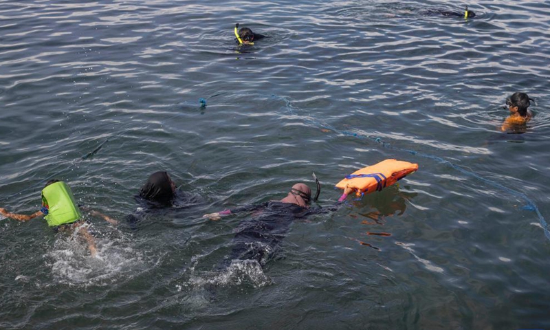 Volunteers swim to pick up plastic wastes during the Marine Debris Festival, held by the local community as a campaign to save the beach from plastics pollution, in Poliwali Mandar district, West Sulawesi, Indonesia, Oct. 3, 2021. (Photo by Yusuf Wahil/Xinhua)