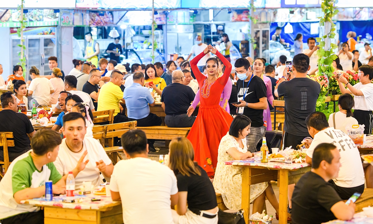 The night market in Hami, Xinjiang is filled with customers on July 16, with a young Uygur girl in traditional costumes performing folk dances. Photo: IC