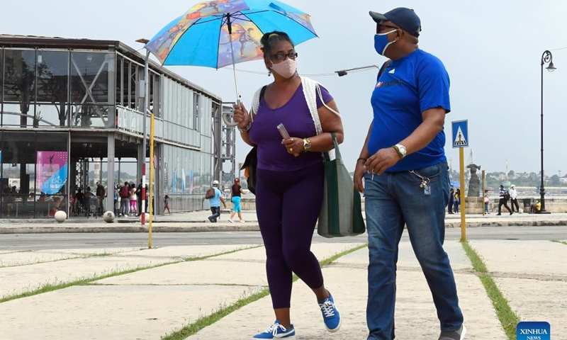 People wearing face masks walk on the street in Havana, Cuba, Sept. 25, 2021. (Photo by Joaquin Hernandez/Xinhua)