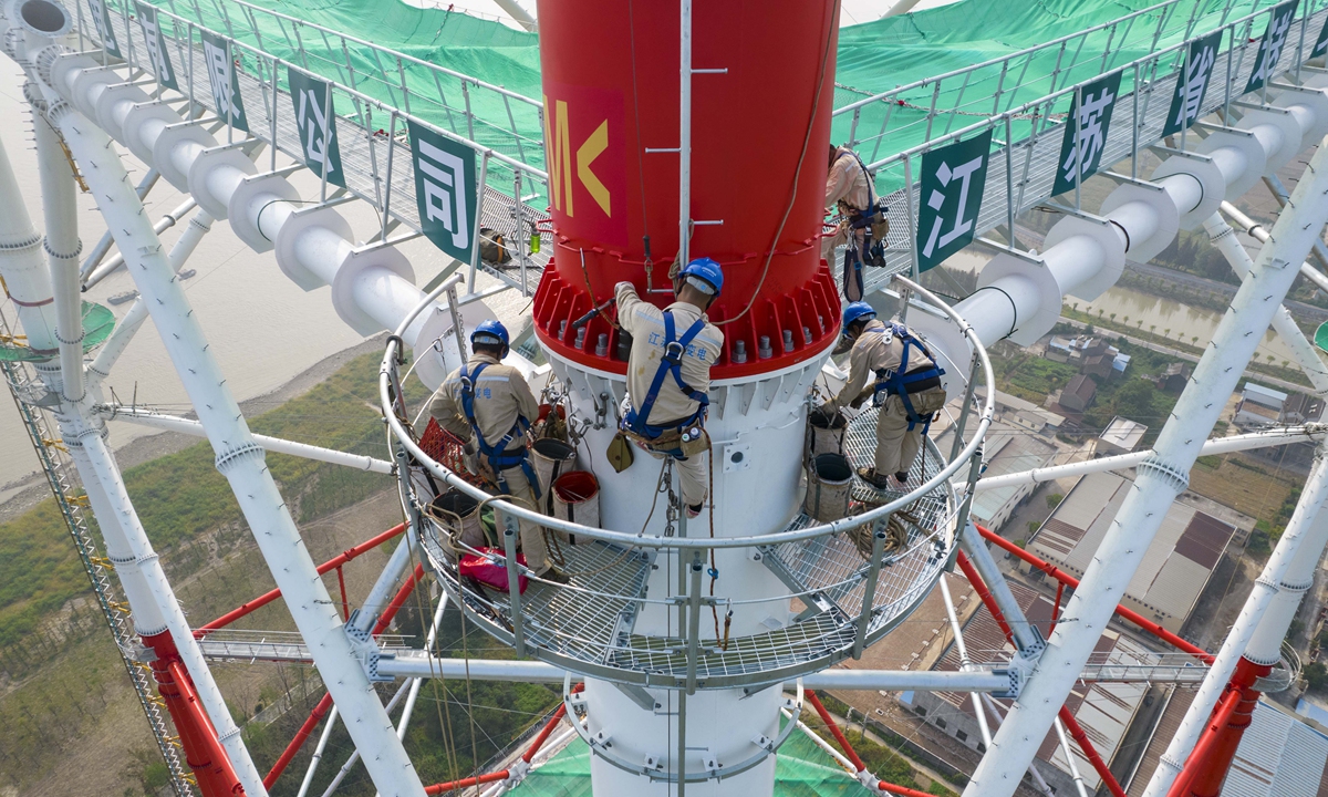 Workers by the side of the Yangtze River assemble a tall transmission tower in Taizhou, East China's Jiangsu Province on Tuesday. The 500-kilovolt tower, with a designed height of 385 meters, is expected to become the world's highest transmission tower. Photo: cnsphoto

