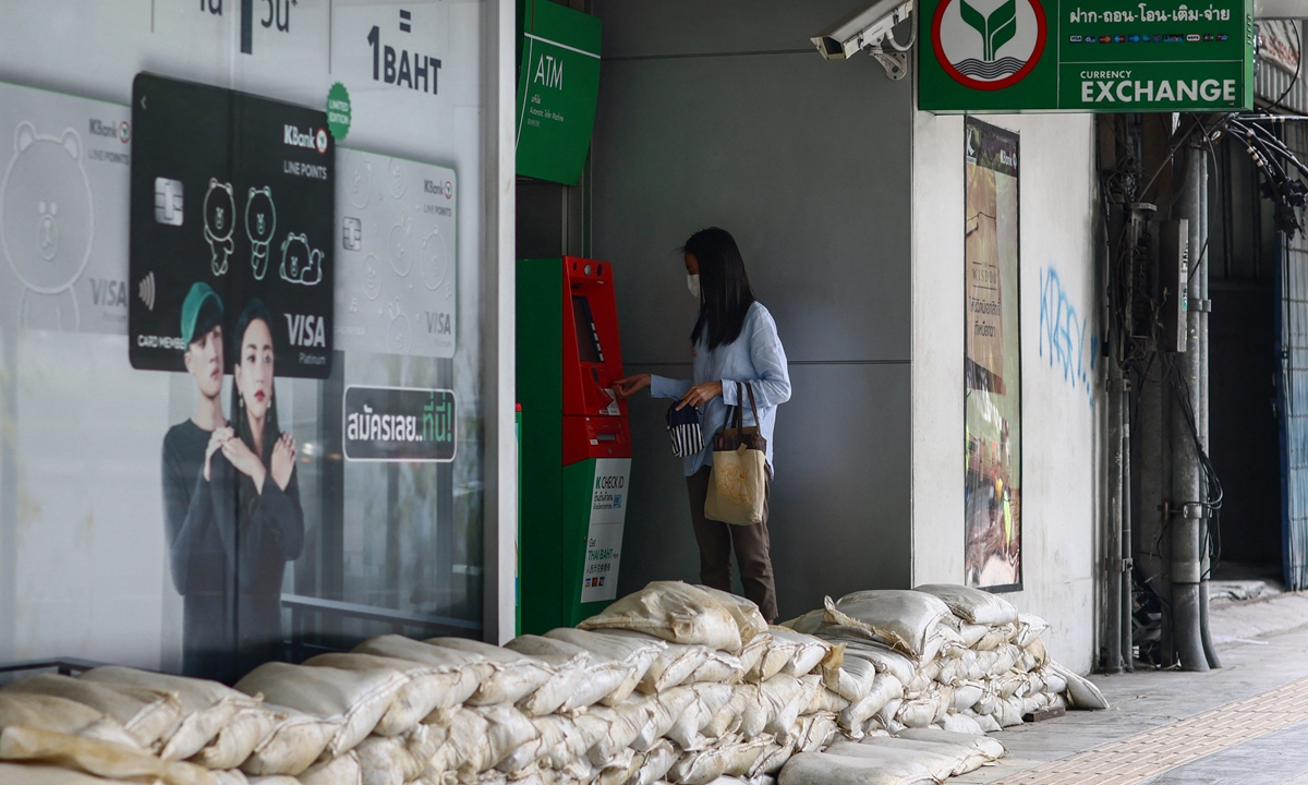 A woman uses an automated teller machine (ATM) next to sandbags, piled up outside a bank as a preventive measure amid flooding across parts of northern and central Thailand, in Bangkok on Tuesday. Photo: AFP