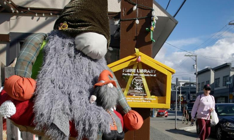 A scarecrow is displayed in front of a store at Steveston Village in Richmond, British Columbia, Canada, on Oct. 6, 2021. Scarecrows are created and placed outside stores at Steveston Village where people are encouraged to vote for the best designs of the year for Steveston Scarecrow Crawl competition.Photo:Xinhua