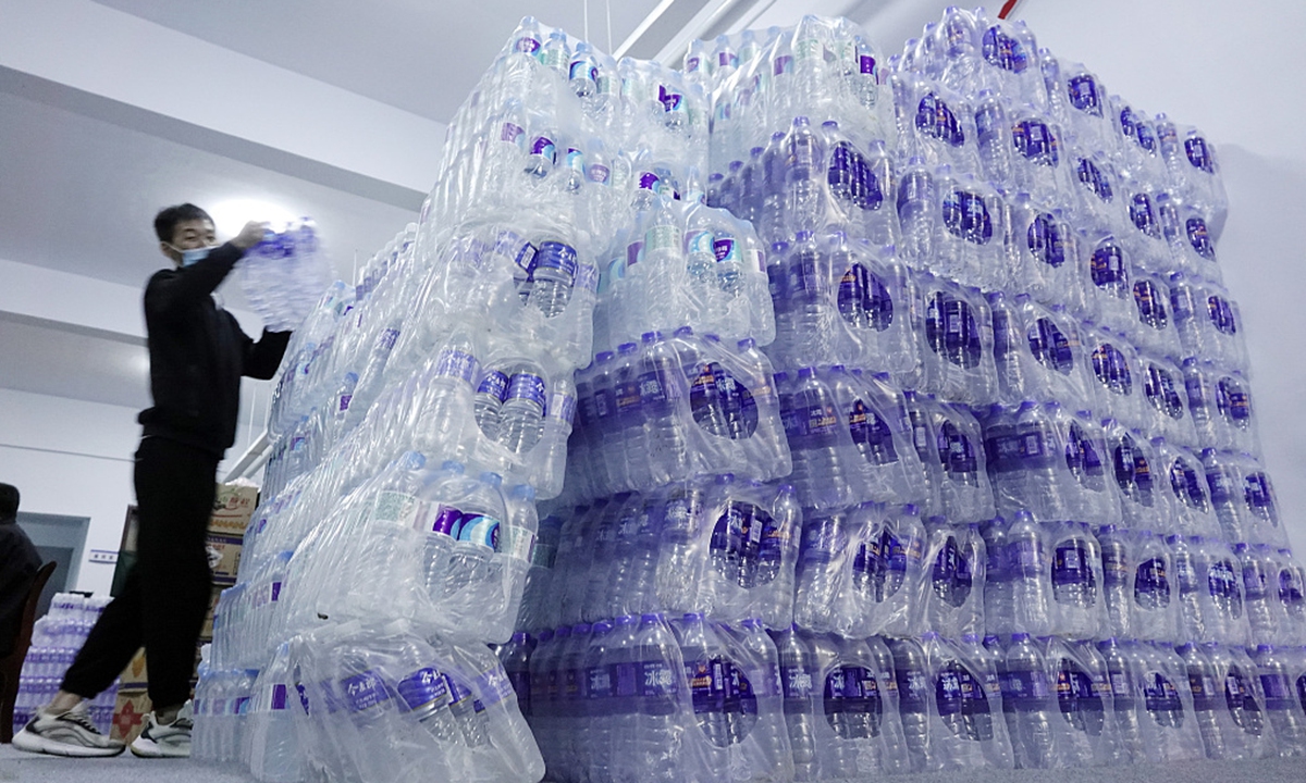An employee carries bottled mineral water donated by enterprises in a relocation site in a gymnasium in Yuncheng, North China's Shanxi Province on October 8, 2021. Photo: CFP