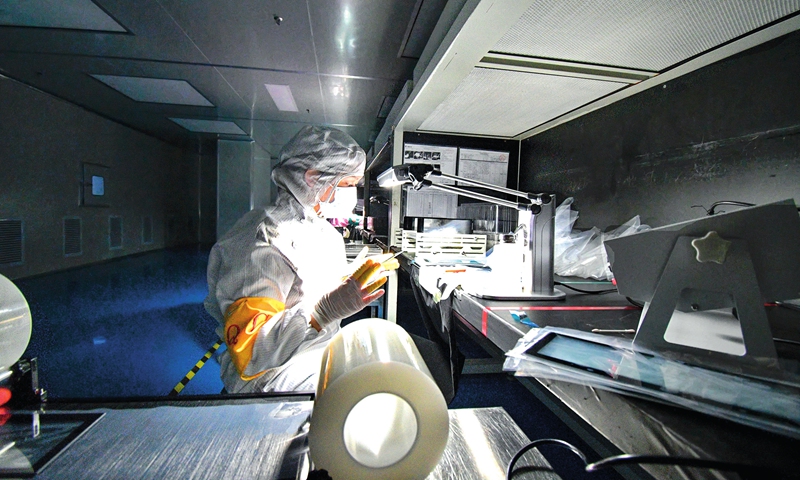 An employee of a photoelectric technology enterprise in Jinxi county, East China's Jiangxi Province makes components for smartphones and tablets at a dust-free workshop on Monday. The county has over recent years made continuous efforts to improve its business environment and foster high-tech industries and emerging sectors as economic anchors. Photo: cnsphoto