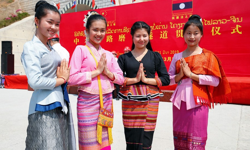 Lao girls pose for pictures at the drilling-through ceremony of Boten Tunnel along the China-Laos railway in Boten of Laos, March 21, 2019.(Photo: Xinhua)