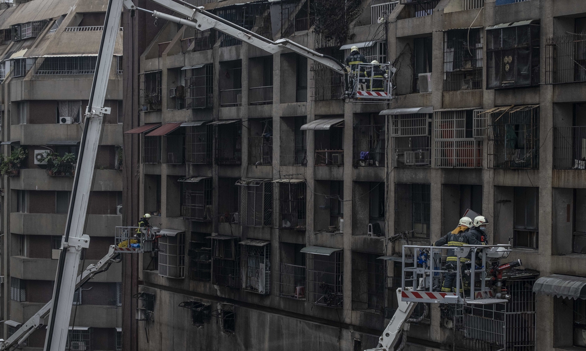 Firemen standing at ladders to inspect the fire damaged area and rescue the injured on Thursday on Taiwan island. Photo: VCG