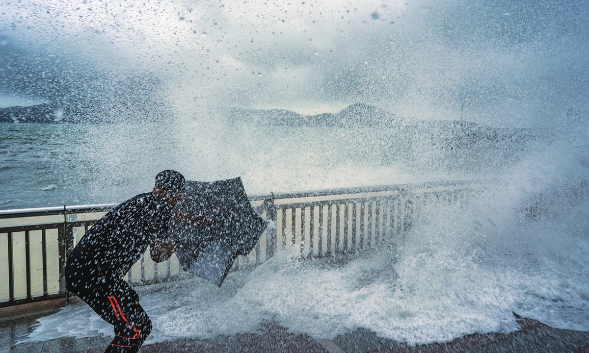 A man braves the waves as they crash over a promenade during a No.8 storm signal raised for Typhoon Kompasu on Wednesday in Hong Kong. Challenged by the second typhoon in less than a week, Hong Kong suspended classes, stock market trading and government services for the day. Photo: VCG