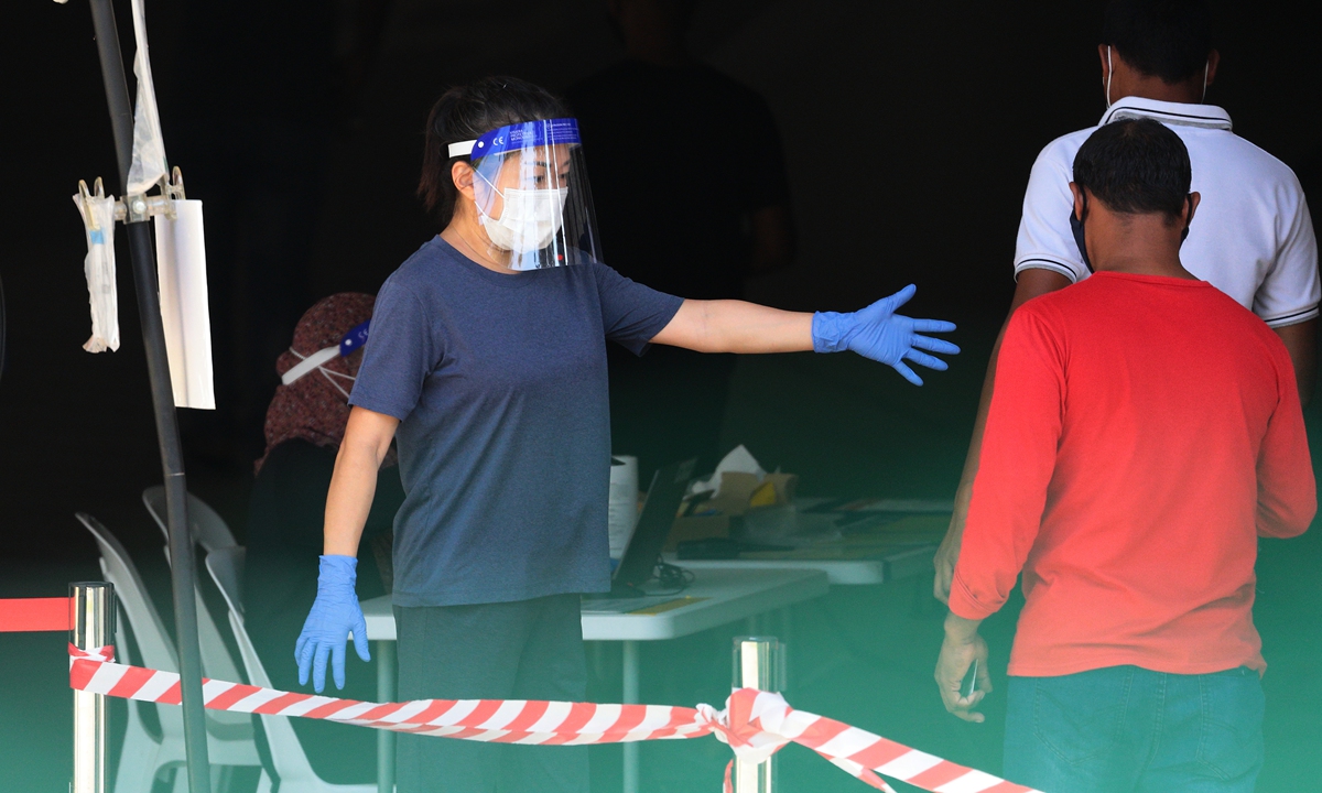 An officer directs the migrant workers in queue to enter a Regional Screening Center to undergo Rostered Routine Testing swab on October 9 in Singapore. Photo: VCG