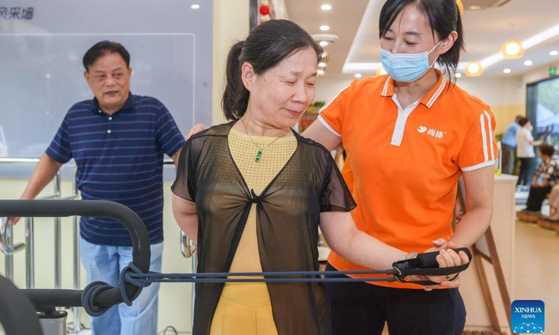 A staff member instructs an elder lady to carry out stretching training at a senior care center in Xuhui District of Shanghai, east China, Oct. 13, 2021.Photo:Xinhua