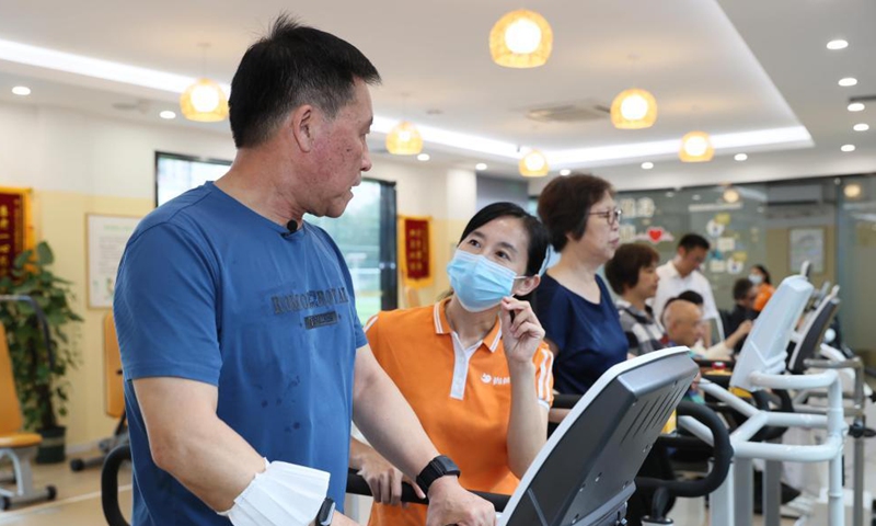 Citizen Shi Baomin experiences a treadmill redesigned for the elders under the guidance of the staff at a senior care center in Xuhui District of Shanghai, east China, Oct. 13, 2021.Photo:Xinhua
