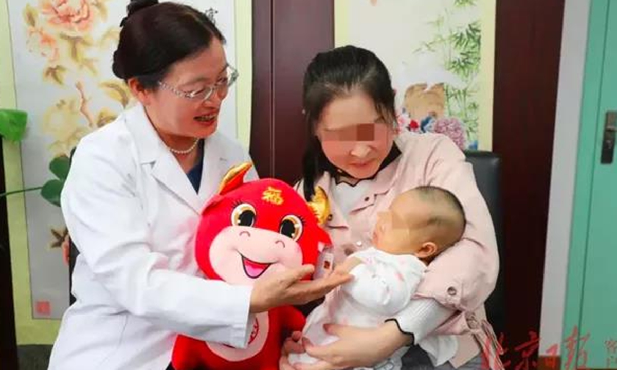 Doctor Ruan Xiangyan and the mother who received ovarian tissue cryopreservation and transplantation carry the healthy baby. Photo: Beijing Daily