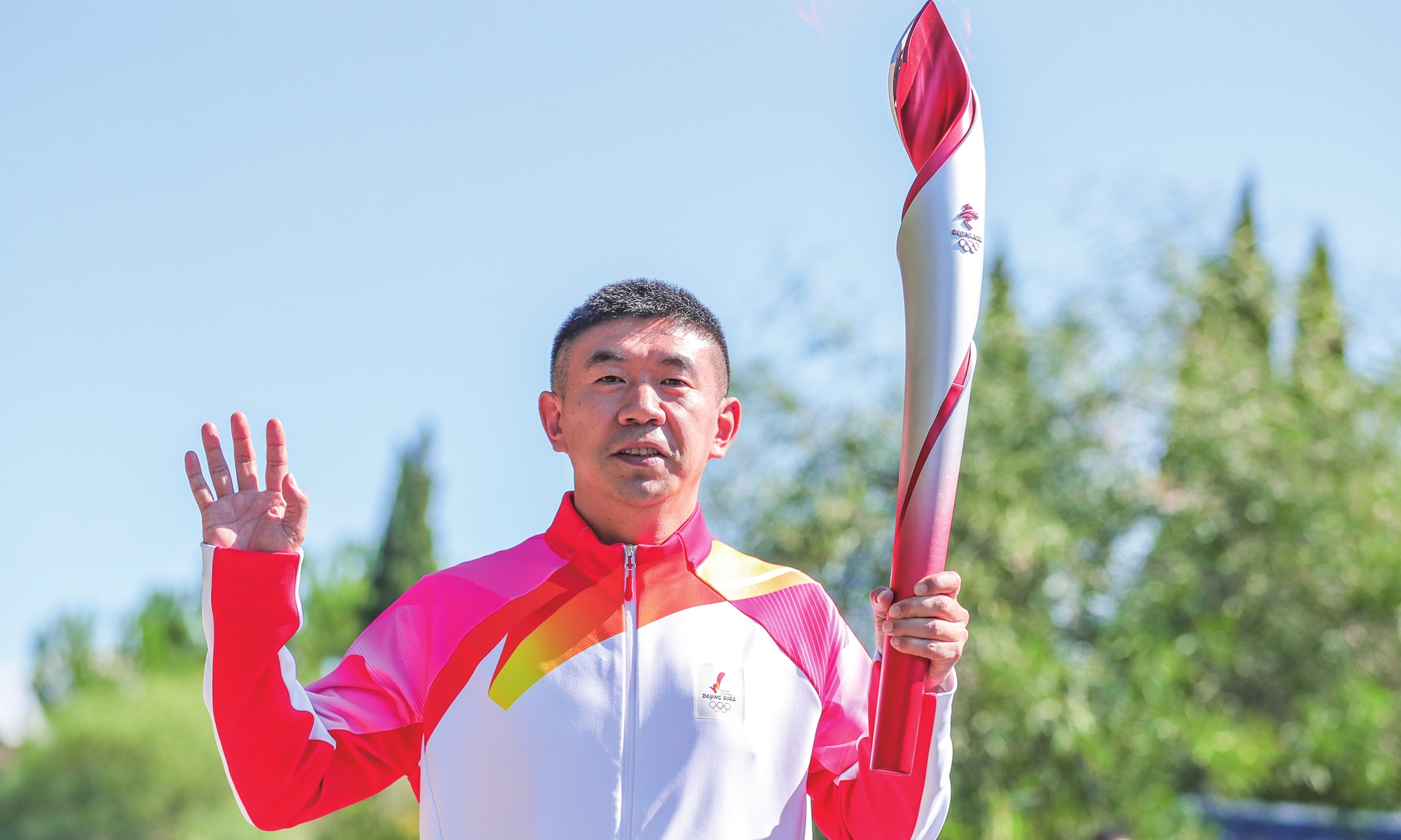 The second torchbearer, former Chinese short-track speed skater Li Jiajun, carries the torch after collecting the flame. Photo: Xinhua