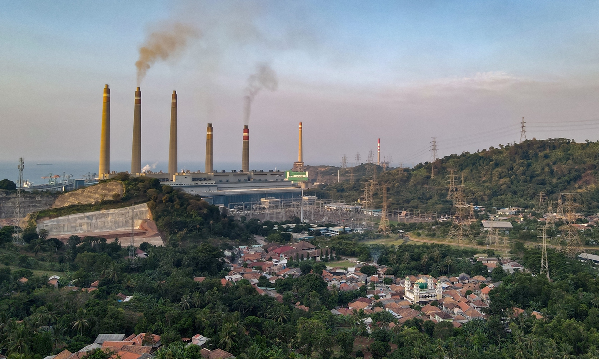 This photo shows village houses as smoke rises from the chimneys at the Suralaya coal power plant in Cilegon. Smokestacks belch noxious fumes into the air from a massive coal-fired power plant on the Indonesian coast on September 21. Photo: AFP


