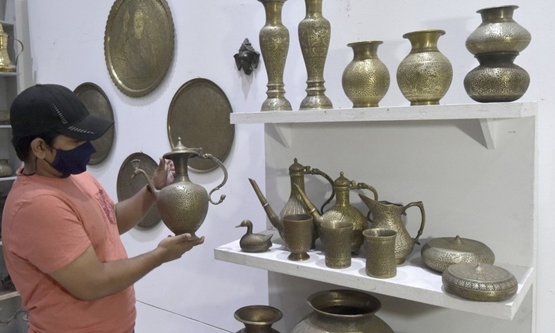 A man views an antique brass utensil during an exhibition featuring folk art and folk music in Dhaka, Bangladesh, Oct. 17, 2021.(Photo: Xinhua)