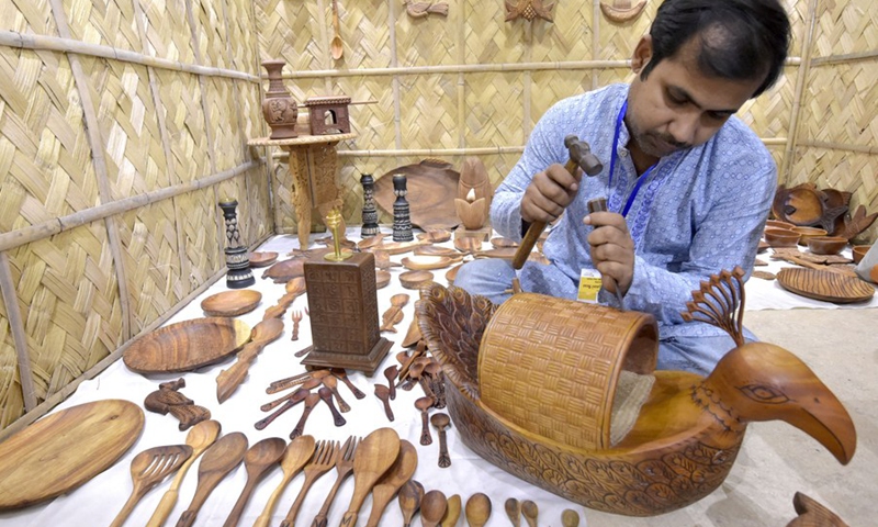 An artist makes a wooden showpiece during an exhibition featuring folk art and folk music in Dhaka, Bangladesh, Oct. 17, 2021.(Photo: Xinhua)