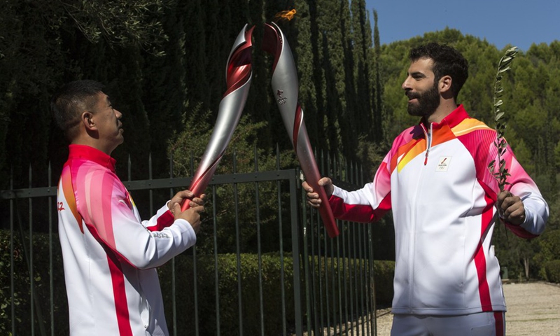 The first torchbearer, Greek alpine ski racer Ioannis Antoniou (R) passes the flame to the second torchbearer Li Jiajun after the Olympic flame lighting ceremony for the Beijing 2022 Olympic Winter Games, in Ancient Olympia, Greece, Oct. 18, 2021. (Photo: Xinhua)
