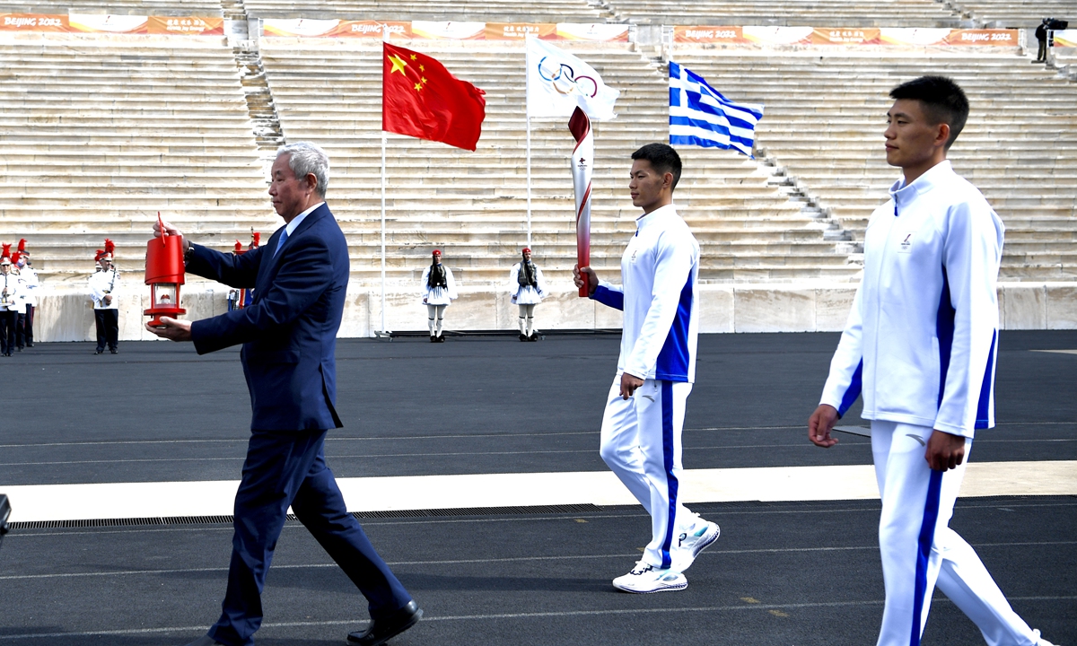 Yu Zaiqing (L), vice president of the Beijing Organizing Committee for the Winter Games, holds the Olympic flame during a handover ceremony at Panathinean Stadium in Athens, Greece on Tuesday. The flame will be flown to Beijing, which will co-host the 2022 Winter Olympics in February.